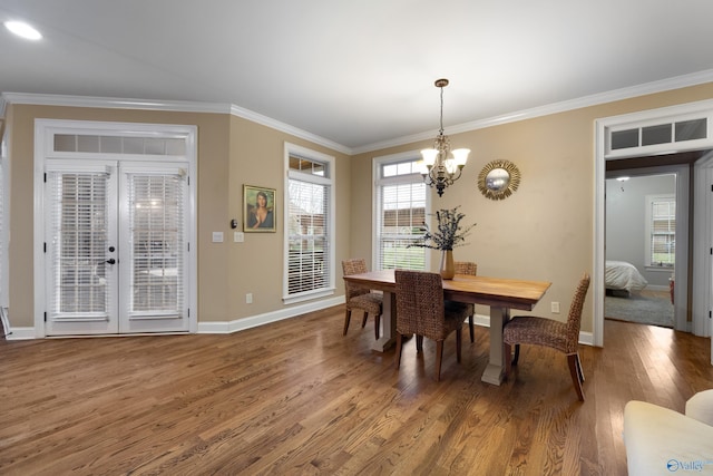 dining area featuring a notable chandelier, crown molding, baseboards, and wood finished floors