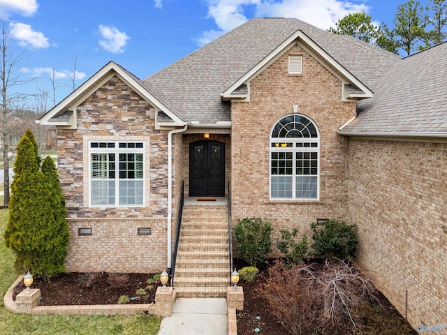 view of front of home featuring crawl space, stone siding, brick siding, and roof with shingles