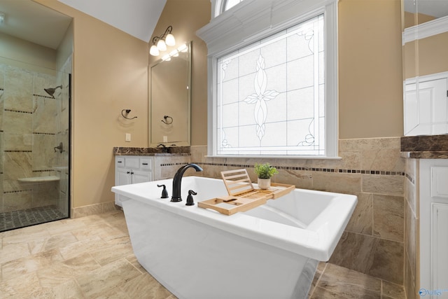 full bath with a freestanding tub, a shower stall, vaulted ceiling, and vanity