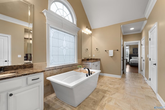 bathroom featuring a soaking tub, crown molding, two vanities, and a sink