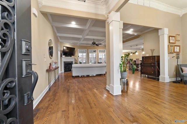 entrance foyer with a fireplace, coffered ceiling, wood finished floors, a ceiling fan, and ornate columns