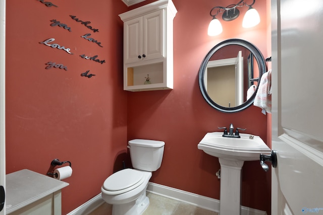 half bath with toilet, tile patterned flooring, and baseboards