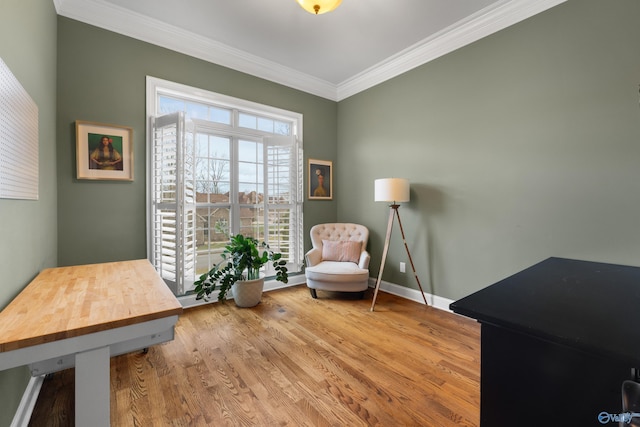 sitting room featuring crown molding, baseboards, and wood finished floors