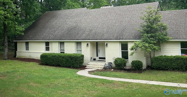 view of front of home with brick siding, a shingled roof, and a front lawn