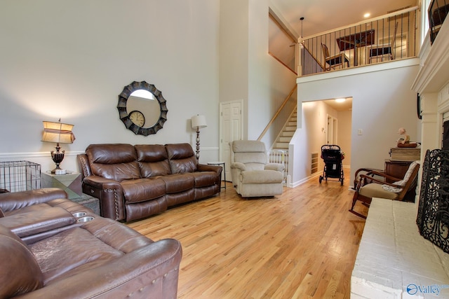 living room featuring baseboards, a high ceiling, wood finished floors, and stairway