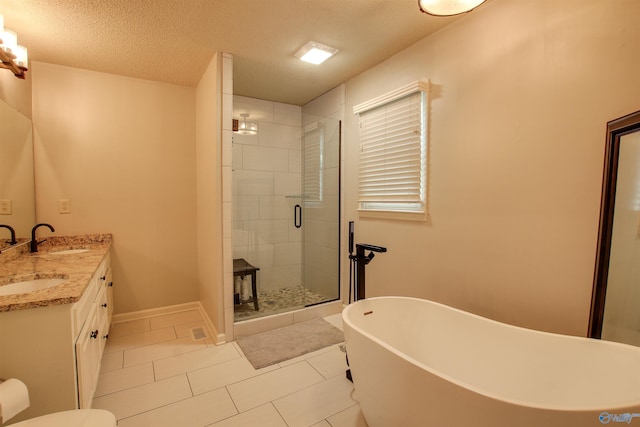 bathroom with a sink, double vanity, a textured ceiling, a soaking tub, and a stall shower
