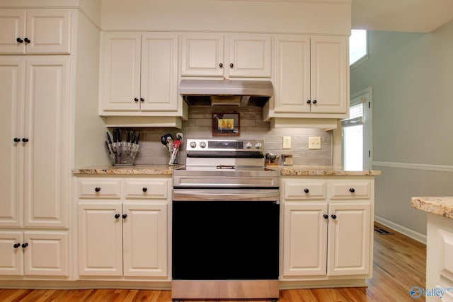 kitchen featuring backsplash, under cabinet range hood, white cabinetry, and stainless steel range with electric cooktop