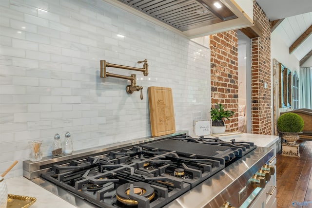 kitchen with stainless steel gas cooktop, vaulted ceiling with beams, and dark hardwood / wood-style floors