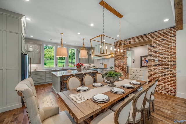 dining area with brick wall, sink, hardwood / wood-style floors, and a notable chandelier