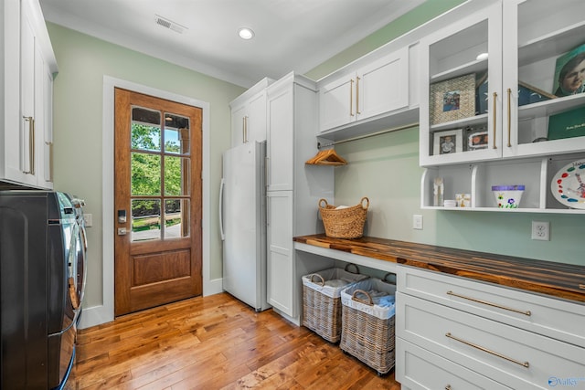 interior space with butcher block countertops, independent washer and dryer, white cabinetry, white refrigerator, and light wood-type flooring