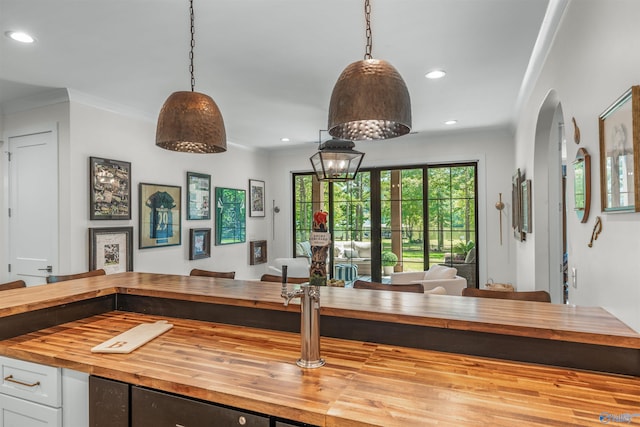 kitchen with arched walkways, recessed lighting, butcher block counters, white cabinets, and crown molding