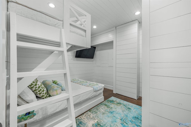 bedroom featuring dark hardwood / wood-style floors and wooden walls