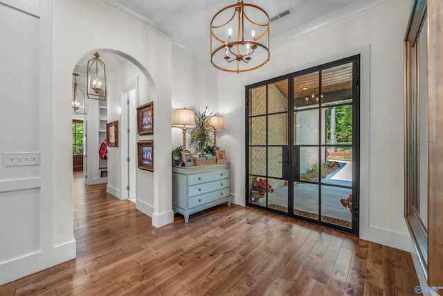 interior space with ornamental molding, wood-type flooring, and a chandelier