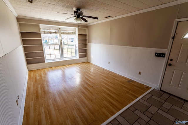 unfurnished room with hardwood / wood-style flooring, ceiling fan, crown molding, and built in shelves