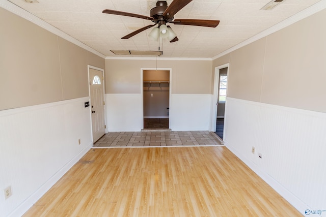 spare room with hardwood / wood-style floors, crown molding, and ceiling fan