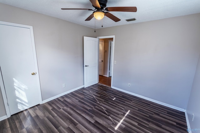 unfurnished bedroom featuring dark hardwood / wood-style flooring, ceiling fan, and a textured ceiling