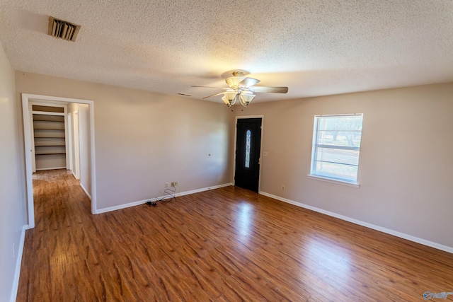 empty room featuring a textured ceiling, wood-type flooring, and ceiling fan