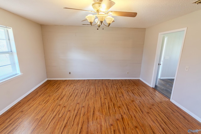 empty room with ceiling fan, light hardwood / wood-style flooring, and a textured ceiling