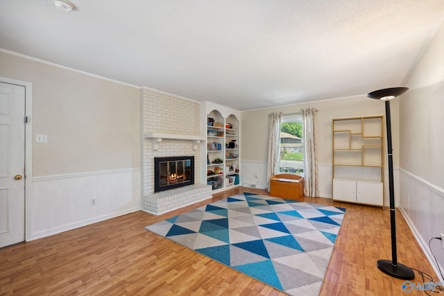 9410 Valley Ln, Huntsville, AL 35803 - unfurnished living room with wood finished floors, wainscoting, a brick fireplace, built in shelves, and ornamental molding