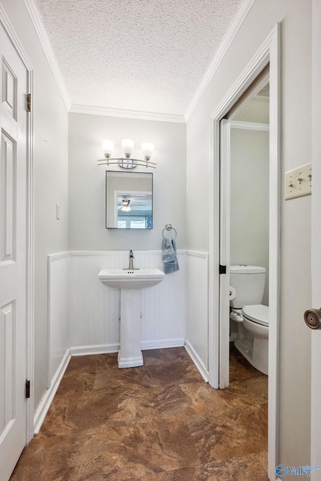 9410 Valley Ln, Huntsville, AL 35803 - bathroom featuring toilet, a textured ceiling, a chandelier, a wainscoted wall, and ornamental molding
