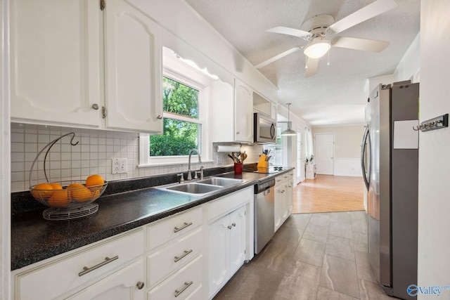 9410 Valley Ln, Huntsville, AL 35803 - kitchen with appliances with stainless steel finishes, a sink, dark countertops, white cabinets, and a textured ceiling