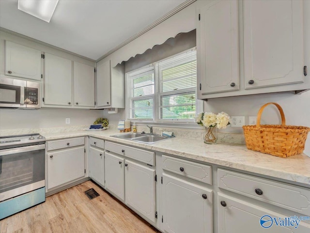 605 Hereford Dr, Athens, AL 35611 - kitchen featuring appliances with stainless steel finishes, a sink, light wood-type flooring, and white cabinetry