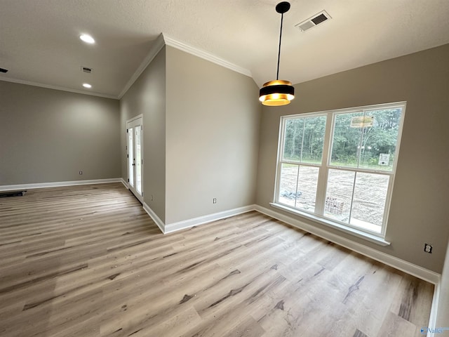 spare room featuring light wood-style floors, baseboards, visible vents, and crown molding