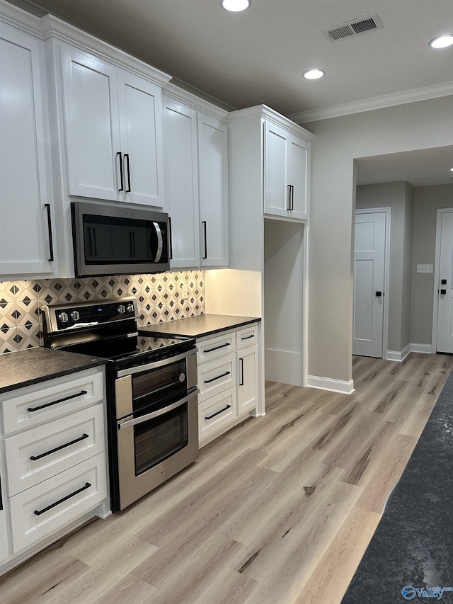 kitchen featuring crown molding, dark countertops, visible vents, decorative backsplash, and appliances with stainless steel finishes