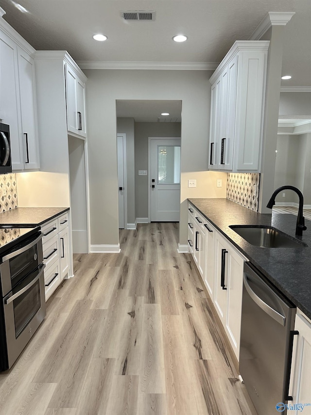 kitchen featuring a sink, visible vents, appliances with stainless steel finishes, light wood finished floors, and crown molding