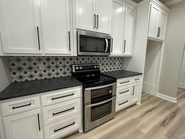 kitchen with light wood finished floors, appliances with stainless steel finishes, white cabinetry, and decorative backsplash