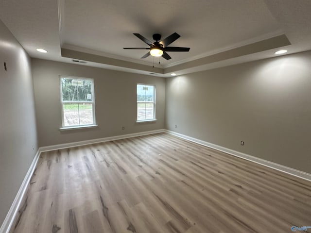 spare room with a ceiling fan, a tray ceiling, baseboards, and wood finished floors