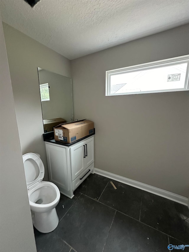 bathroom with toilet, a textured ceiling, baseboards, and tile patterned floors