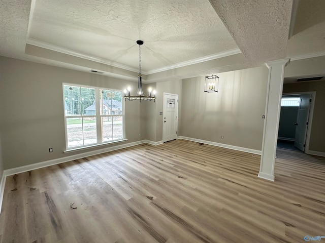 unfurnished dining area with a tray ceiling, visible vents, a textured ceiling, and wood finished floors