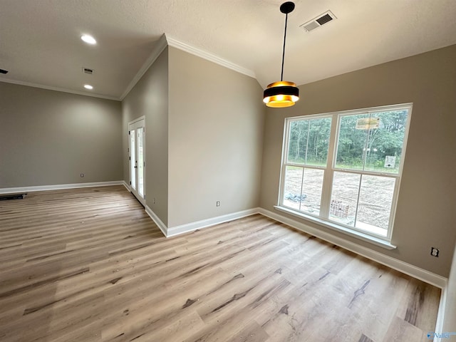 empty room featuring light wood-style floors, visible vents, ornamental molding, and baseboards