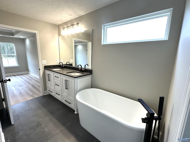 bathroom featuring a wealth of natural light, a textured ceiling, and a sink