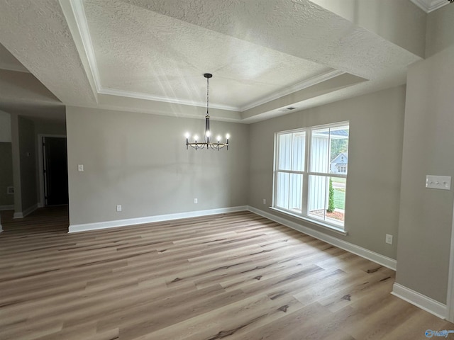 unfurnished dining area with light wood finished floors, a tray ceiling, and baseboards