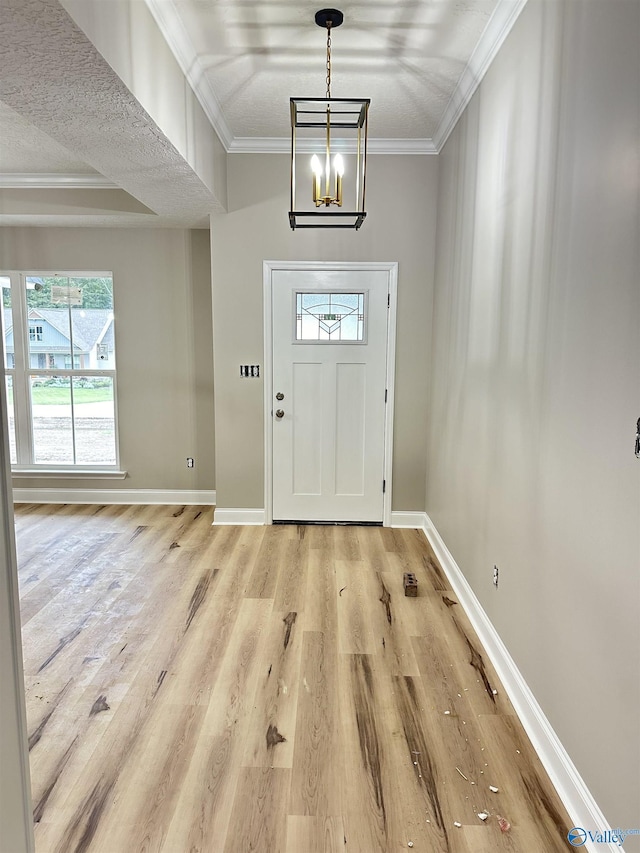 entrance foyer featuring a notable chandelier, ornamental molding, light wood-style flooring, and baseboards