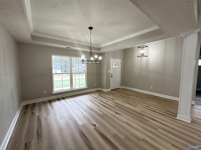 unfurnished dining area with a textured ceiling, wood finished floors, a raised ceiling, and a notable chandelier