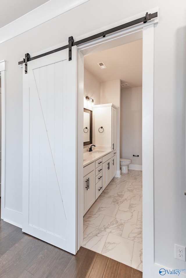 bathroom featuring hardwood / wood-style floors, dual bowl vanity, and toilet