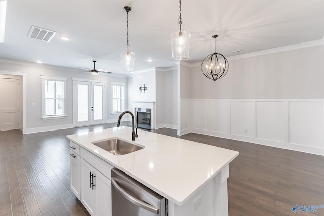 kitchen featuring ceiling fan with notable chandelier, stainless steel dishwasher, an island with sink, dark hardwood / wood-style floors, and sink