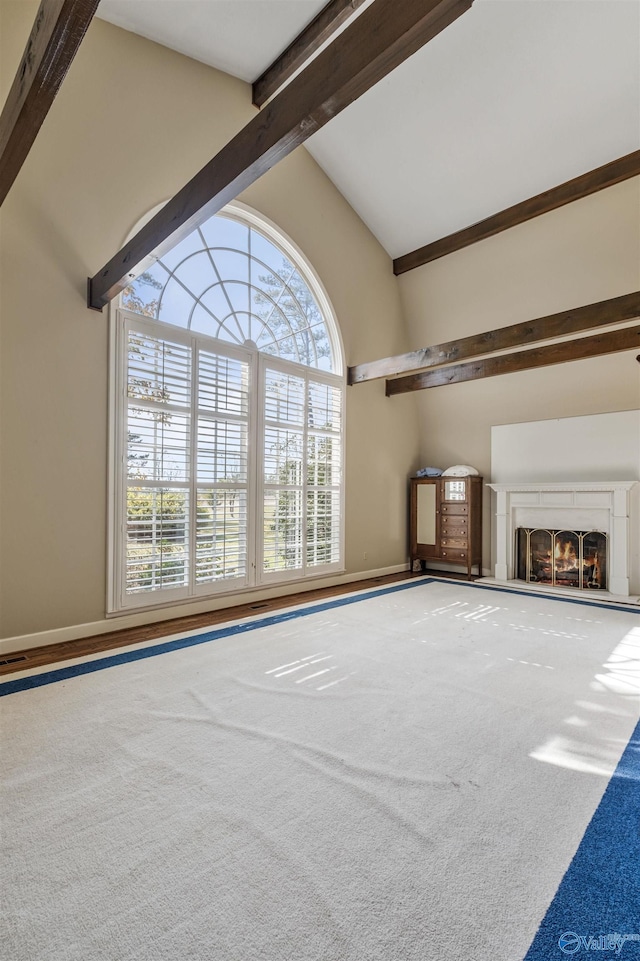 unfurnished living room with carpet flooring, high vaulted ceiling, beam ceiling, and a healthy amount of sunlight