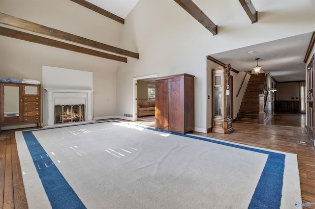 unfurnished living room with a high ceiling, beamed ceiling, and dark wood-type flooring