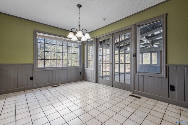 unfurnished dining area with a textured ceiling, ceiling fan with notable chandelier, and light tile patterned floors