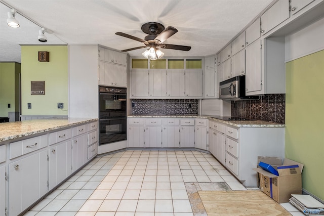 kitchen featuring rail lighting, ceiling fan, black appliances, and light stone counters