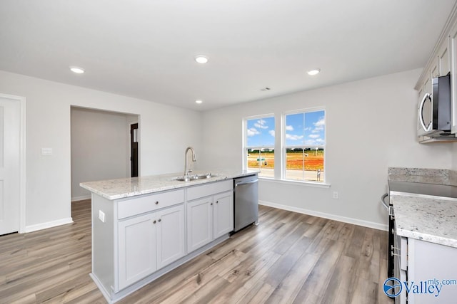 kitchen featuring white cabinets, an island with sink, light hardwood / wood-style floors, appliances with stainless steel finishes, and sink