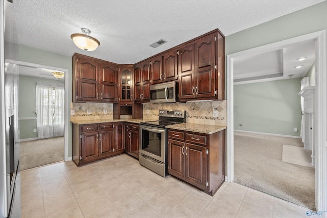 221 Badger Dr, Harvest, AL 35749 - kitchen with stainless steel appliances, light carpet, baseboards, light stone counters, and decorative backsplash