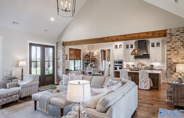 living room with high vaulted ceiling, french doors, dark hardwood / wood-style flooring, and a notable chandelier