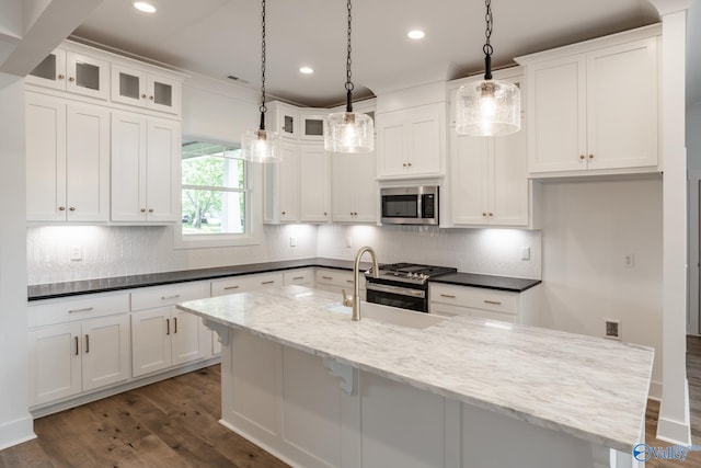 kitchen featuring dark stone counters, dark hardwood / wood-style flooring, decorative backsplash, sink, and appliances with stainless steel finishes