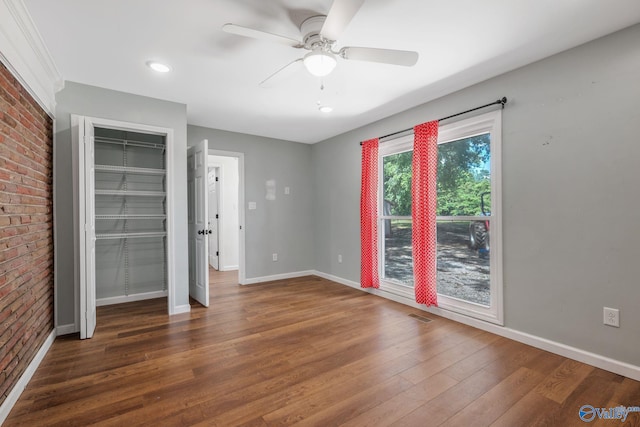 3621 Al Highway 36, Moulton, AL 35650 - unfurnished bedroom featuring wood finished floors, baseboards, brick wall, and a ceiling fan