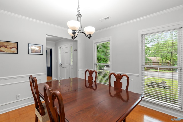 dining room with crown molding, a chandelier, light wood-type flooring, and a wealth of natural light